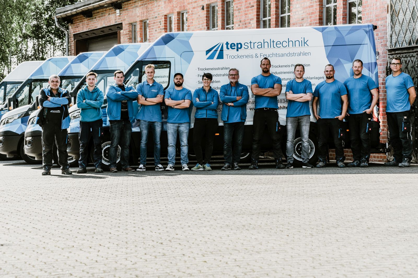 Teamfoto vor fünf mit Firmenlogo Beschrifteten Bullis